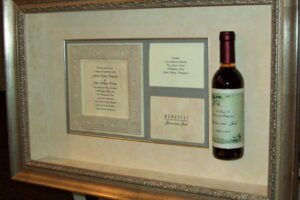 Custom-framed wedding invitation and wine bottle